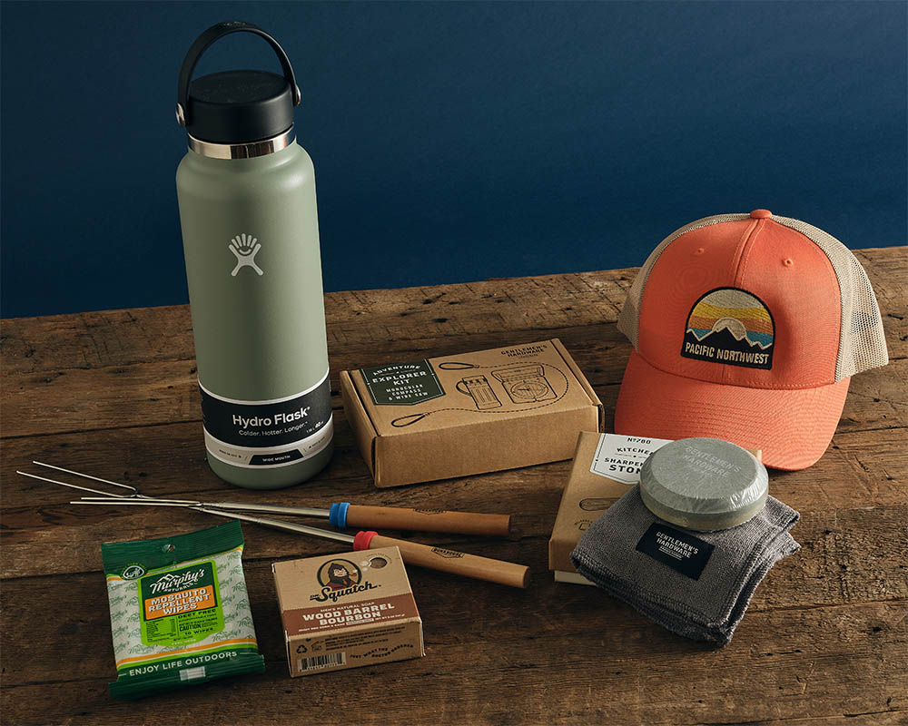 Image of outdoor adventure accessories including a hat, water bottle, marshmallow roasting sticks, etc.