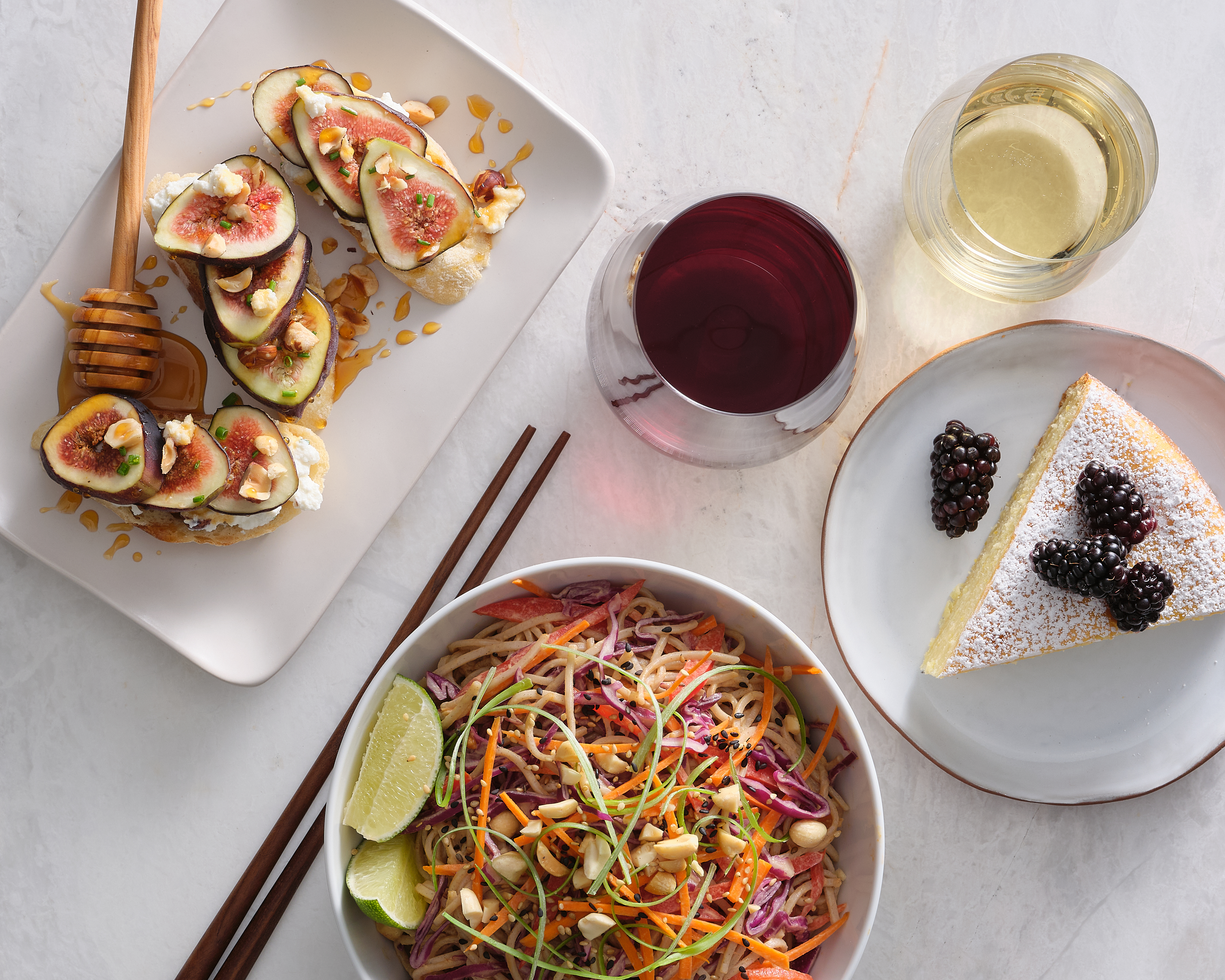 Fig bruschetta, noodles, cake, and glasses of red and white wine
