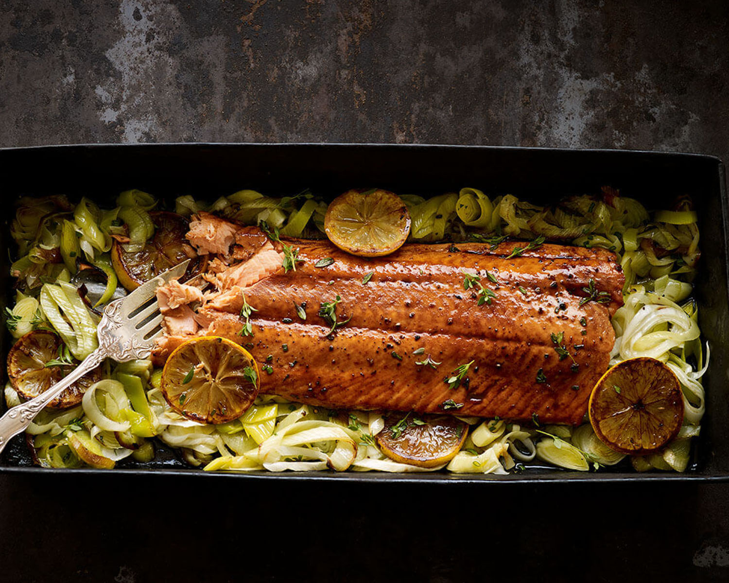 Baked salmon fillet in a roasting pan with lemons