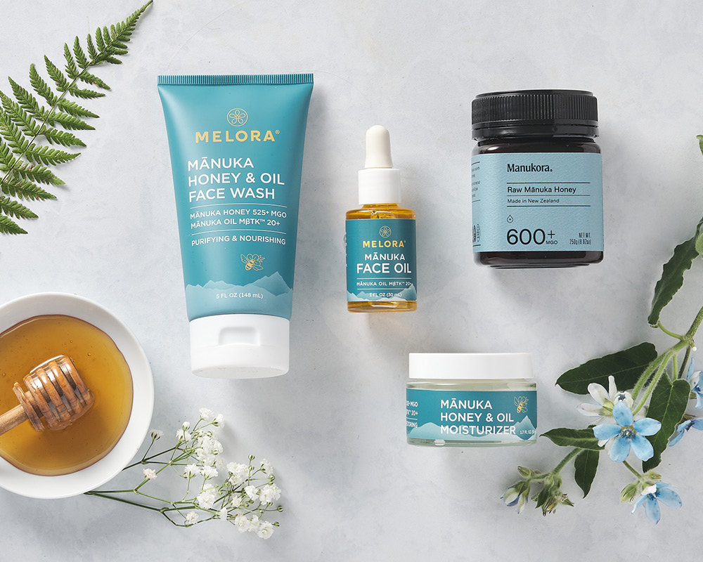 Manuka honey and skincare products styled with honey, flowers, and a fern
