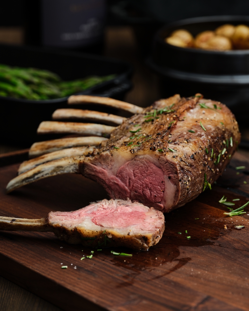 Roasted Rack of Lamb with One Piece Sliced on Cutting Board