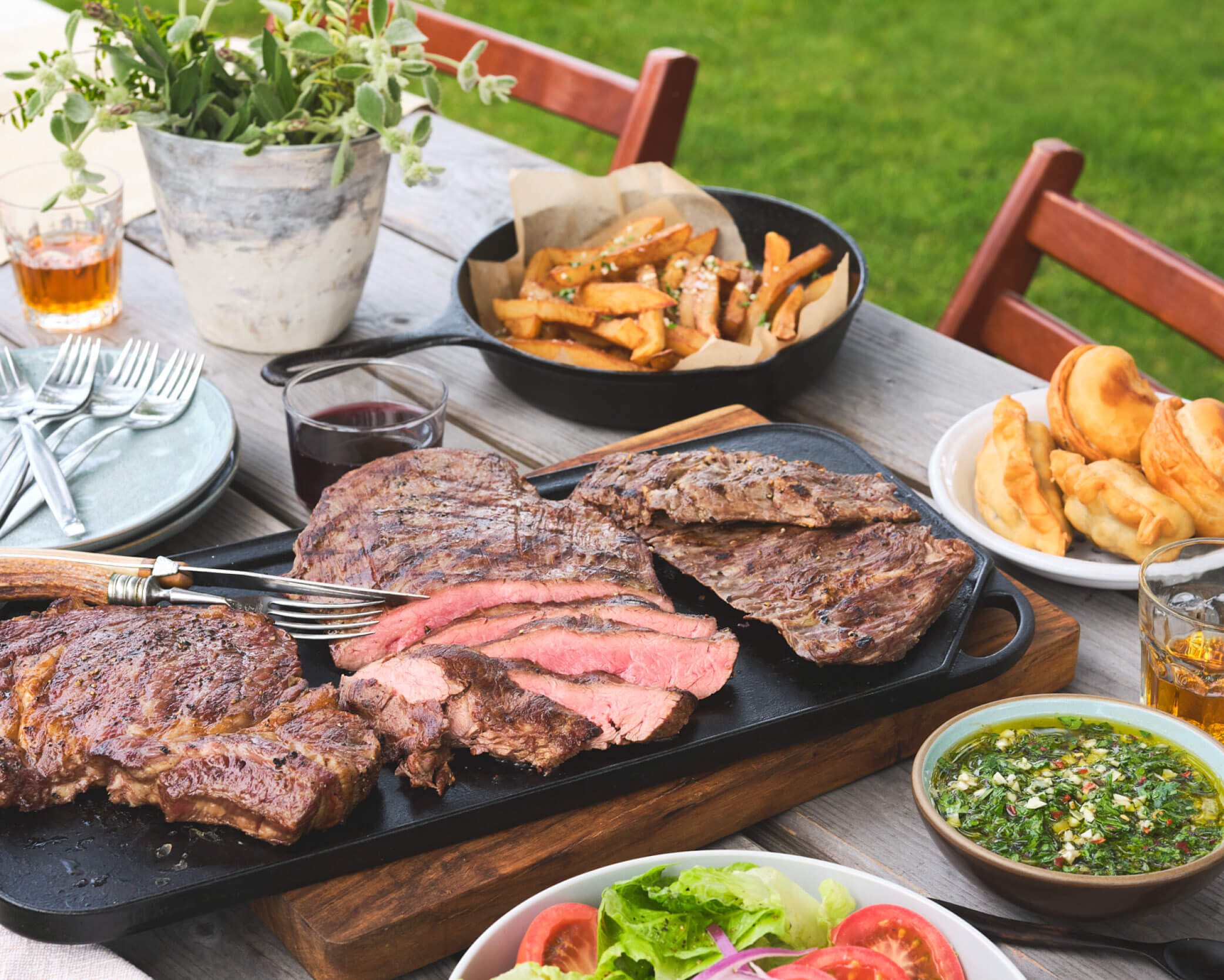 Picnic table with plates full of grilled food
