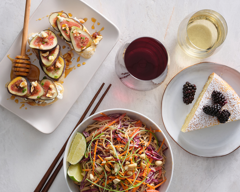 Fig bruschetta, noodles, cake, and glasses of red and white wine
