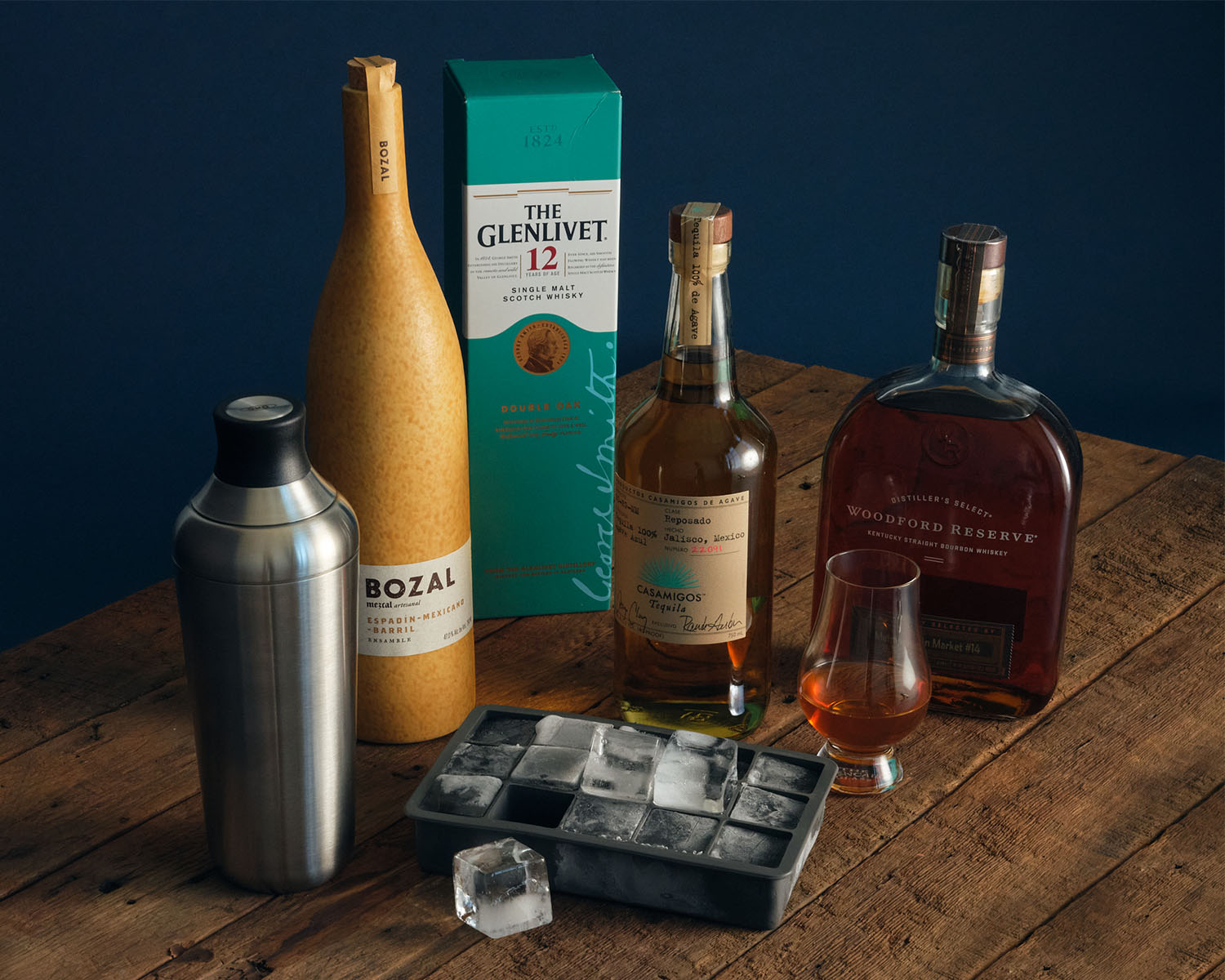 Image of various bottles of alcohol, a cocktail shaker, and ice cube tray.