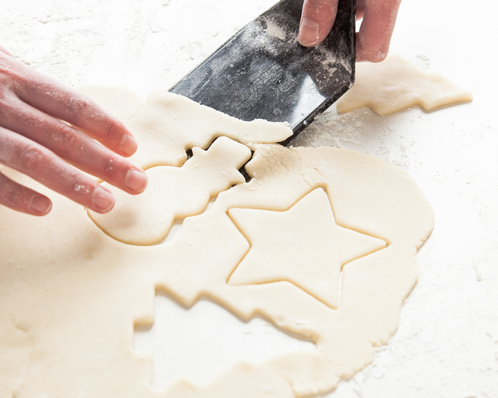 Sugar cookie cutouts being lifted from dough