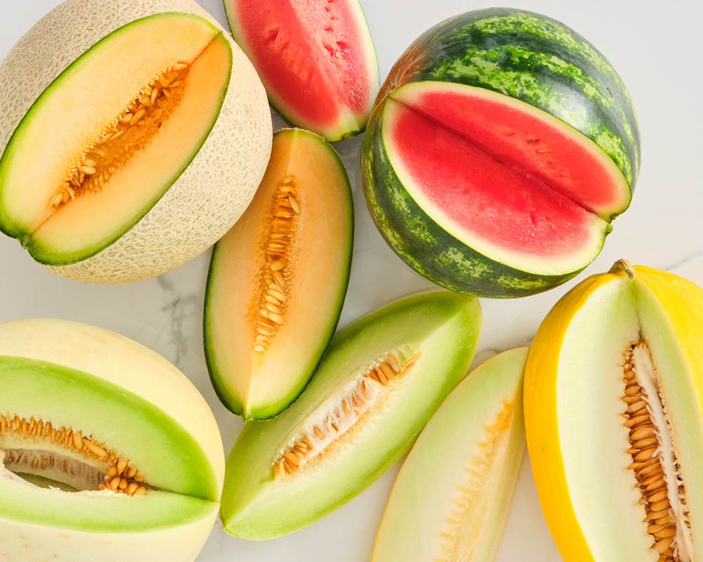 An assortment of melons with cut wedges